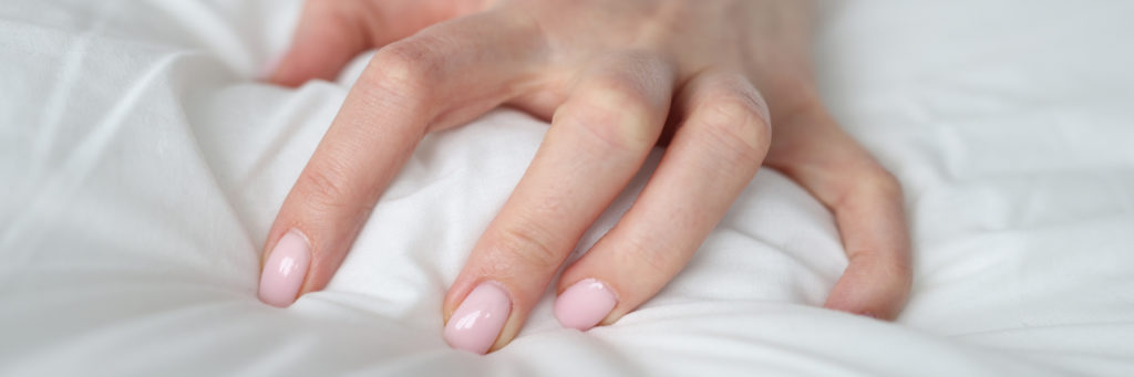 Main de femme qui agrippe la couette pendant le sexe